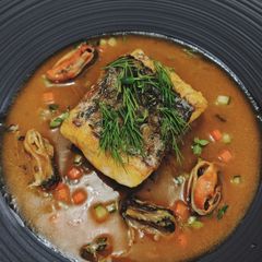 A picture of Seabass served with mussels in tomato sauce.