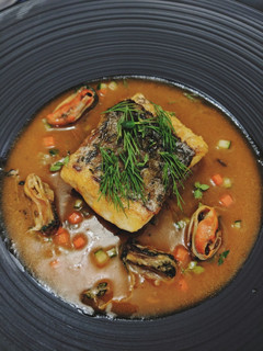 A picture of Seabass served with mussels in tomato sauce.