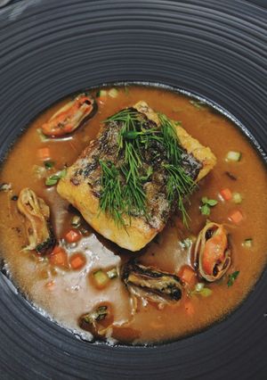 A picture of Seabass served with mussels in tomato sauce.