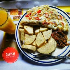 A picture of Fried yam, eggs and orange juice.