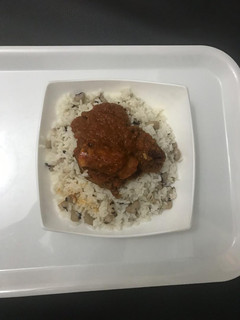 A picture of Chicken Stew Served with Rice and Bean.