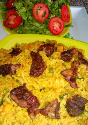 A picture of Jollof rice with roasted meat and salad.