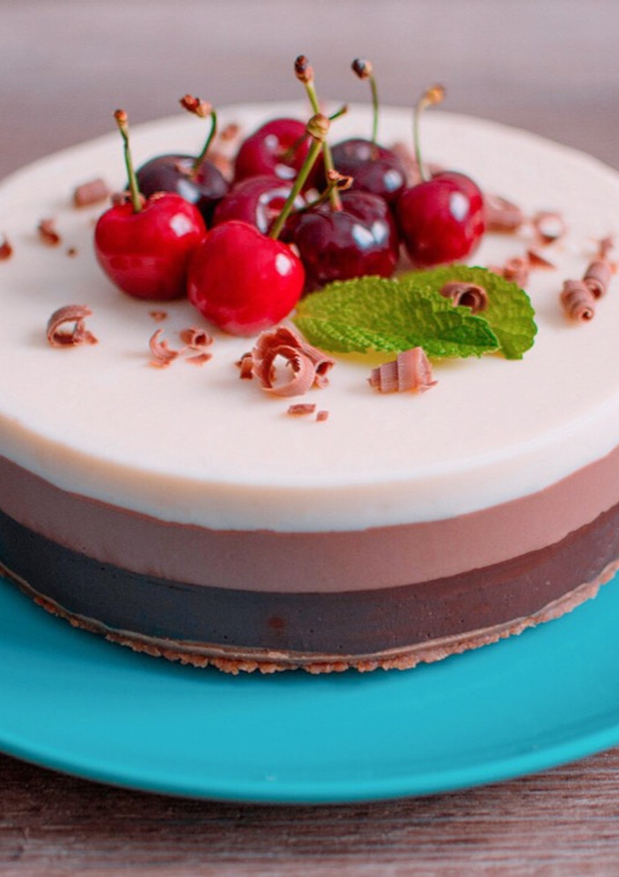 Una foto de Tarta de tres chocolates con cerezas