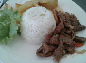 Una foto de Lomo salteado con una porción de arroz y papas fritas