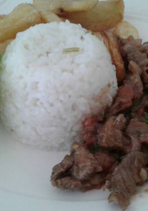 Una foto de Lomo salteado con una porción de arroz y papas fritas