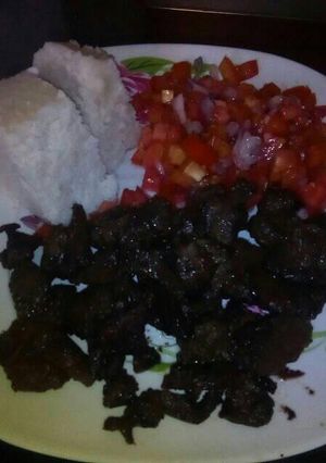 A picture of Fried liver with ugali and kachumbari.
