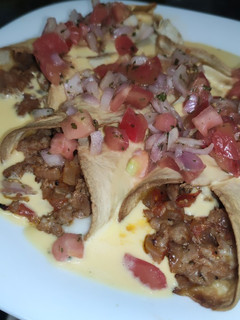 Una foto de Tacos de ternera bañados en queso cheddar