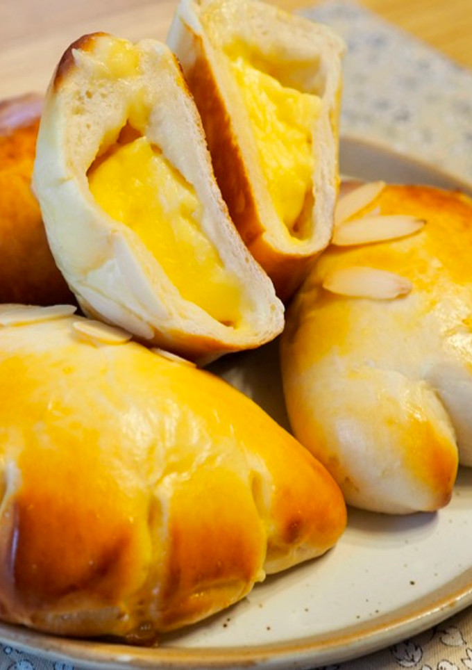 Una foto de Pan relleno de crema pastelera (クリームパン) / Bollo japonés