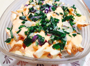 Una foto de Papas fritas con cheddar y cebollita de verdeo