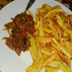 A picture of Kibda (Egyptian liver sauce) and French fries.
