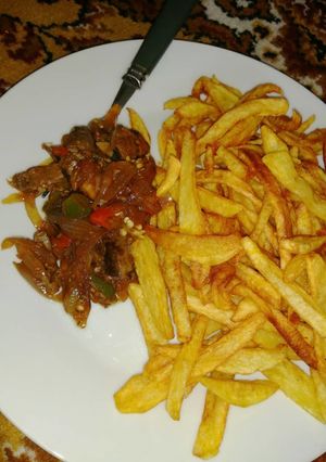 A picture of Kibda (Egyptian liver sauce) and French fries.