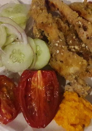 Una foto de Tiras de pollo apanadas con ensalada de pepinos y cebolla morada