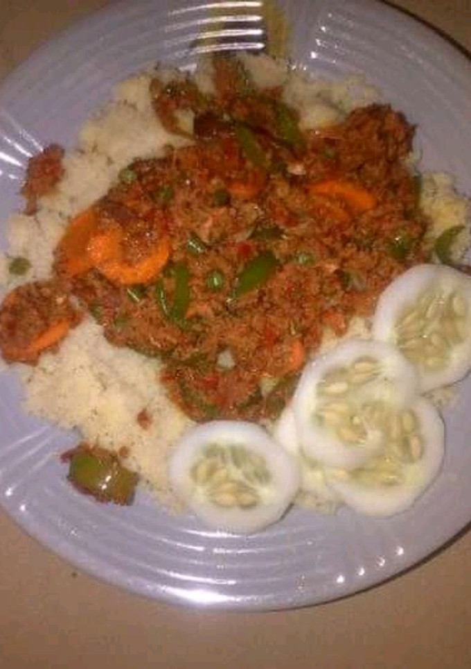 A picture of Couscous with meat sauce and cucumber.