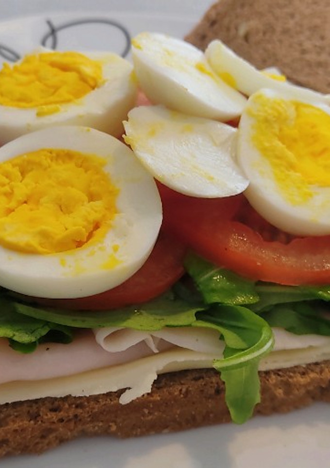 Una foto de Sándwich de centeno con pavo, queso, rúcula, tomate y huevo