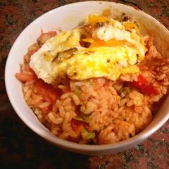 A picture of Rice with fried egg and tomato.