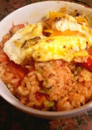 A picture of Rice with fried egg and tomato.