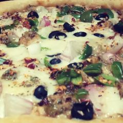 A picture of Malai boti pizza with white sauce.