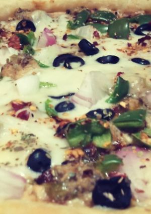 A picture of Malai boti pizza with white sauce.