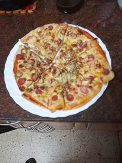 Una foto de Pizza de jamón cocido, salchicha y aceitunas