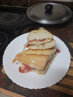 Una foto de Bocadillo de cebolla caramelizada, queso de cabra, tortilla francesa y jamón serrano