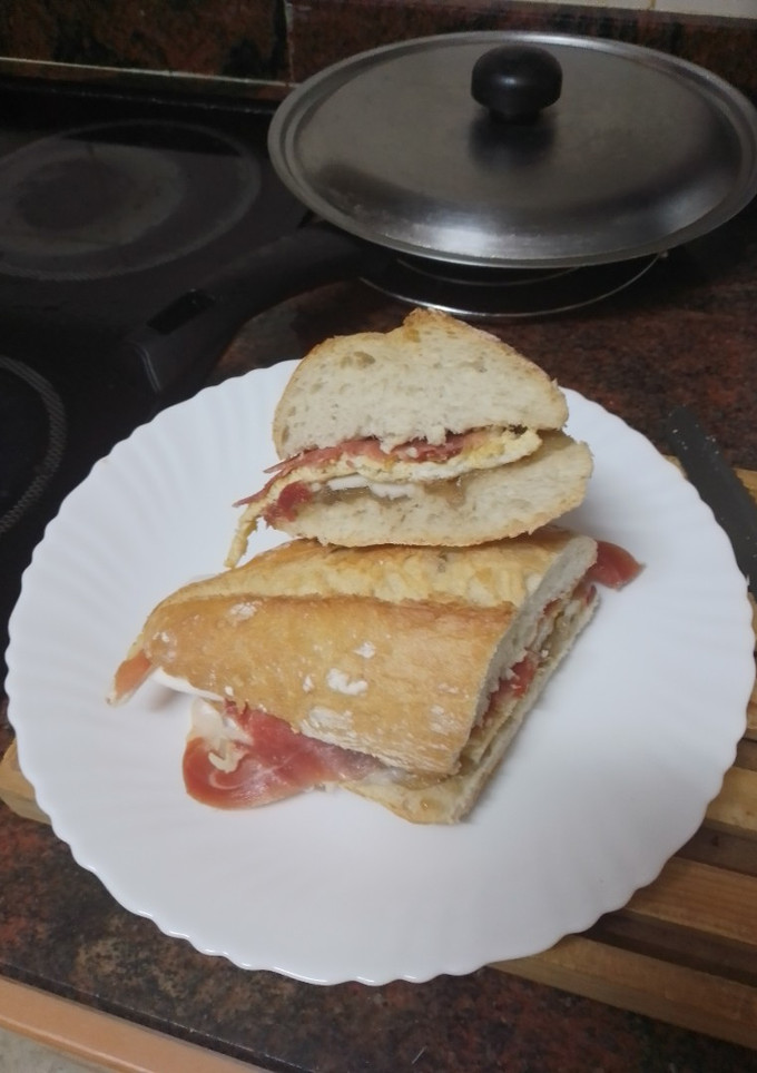 Una foto de Bocadillo de cebolla caramelizada, queso de cabra, tortilla francesa y jamón serrano