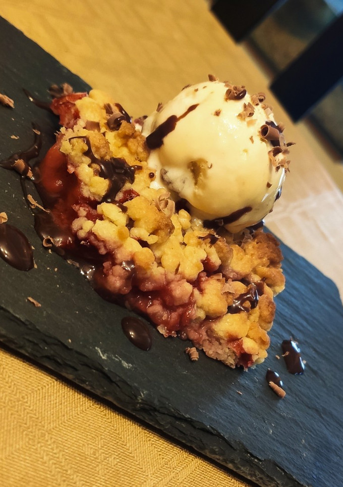 Una foto de Crumble de fresas con helado de vainilla y chocolate