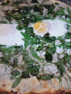 Una foto de Pizza con rúcula y canónigos, queso trufa y huevo