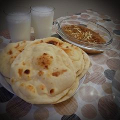 A picture of Chicken Qorma with homemade naans and lassi.
