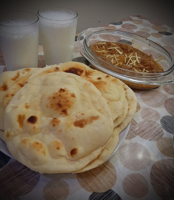 A picture of Chicken Qorma with homemade naans and lassi.