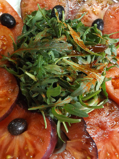 Una foto de Fuente de tomates Monterrosa y tomates azules con rúcula