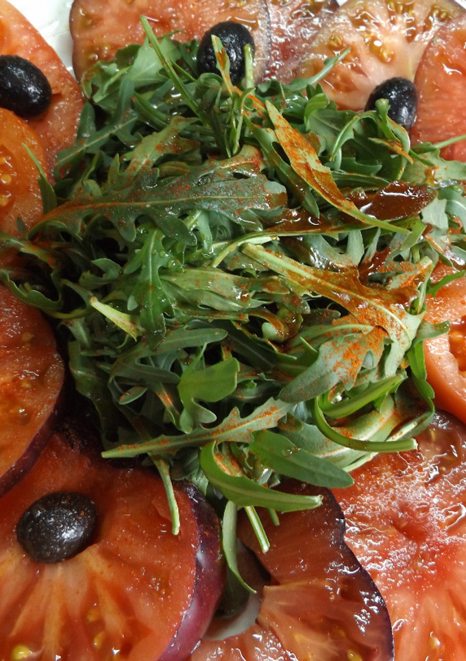 Una foto de Fuente de tomates Monterrosa y tomates azules con rúcula
