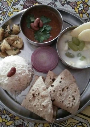 A picture of Rajma, rice, sukhe aalu, roti, fruit yoghurt.