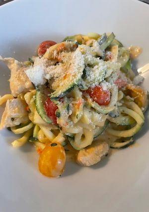 Una foto de Espaguetis de calabacín con pollo, albahaca y salsa de queso feta con tomates cherry