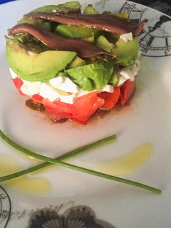 Una foto de Timbal de tomate, aguacate, queso y anchoas