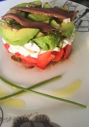 Una foto de Timbal de tomate, aguacate, queso y anchoas