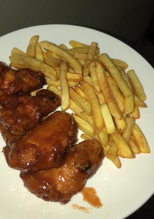 Una foto de Alitas en salsa BBQ con papas fritas
