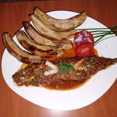 A picture of Fried sardine in coconut, tomato sauce and fried green bananas.