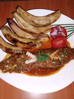 A picture of Fried sardine in coconut, tomato sauce and fried green bananas.