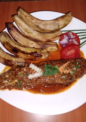 A picture of Fried sardine in coconut, tomato sauce and fried green bananas.