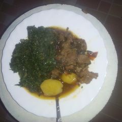 A picture of Beef stew served with greens.