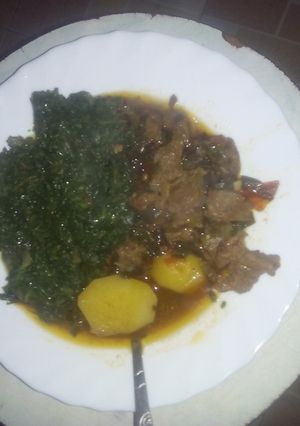 A picture of Beef stew served with greens.