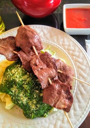 Una foto de Tallarines en salsa verde con brochetas de anticucho