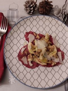 Foto di Carpaccio di carciofi bresaola petali di parmigiano noci