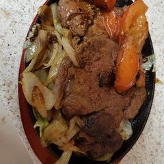 A picture of 16oz Sizzling Rump Steak on a platter with Mushrooms onions.