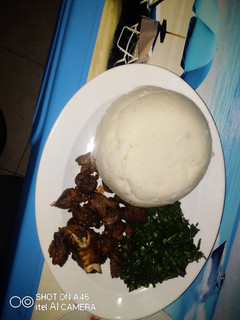 A picture of Pan Fried goat meat served with kales.