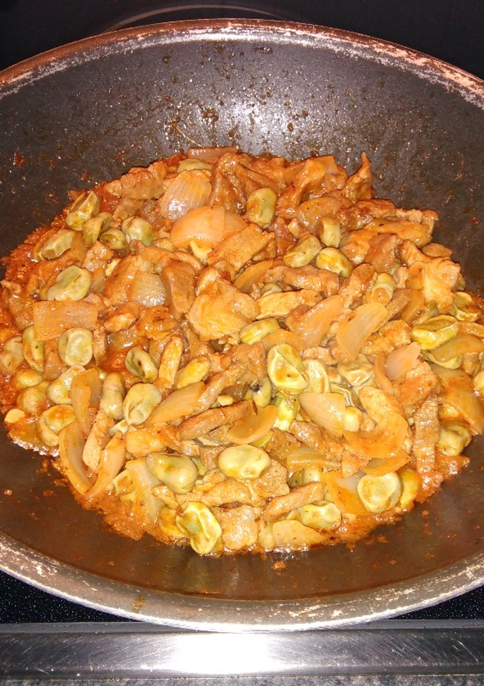 Una foto de Wok de chuletas de aguja con habas y cebolla