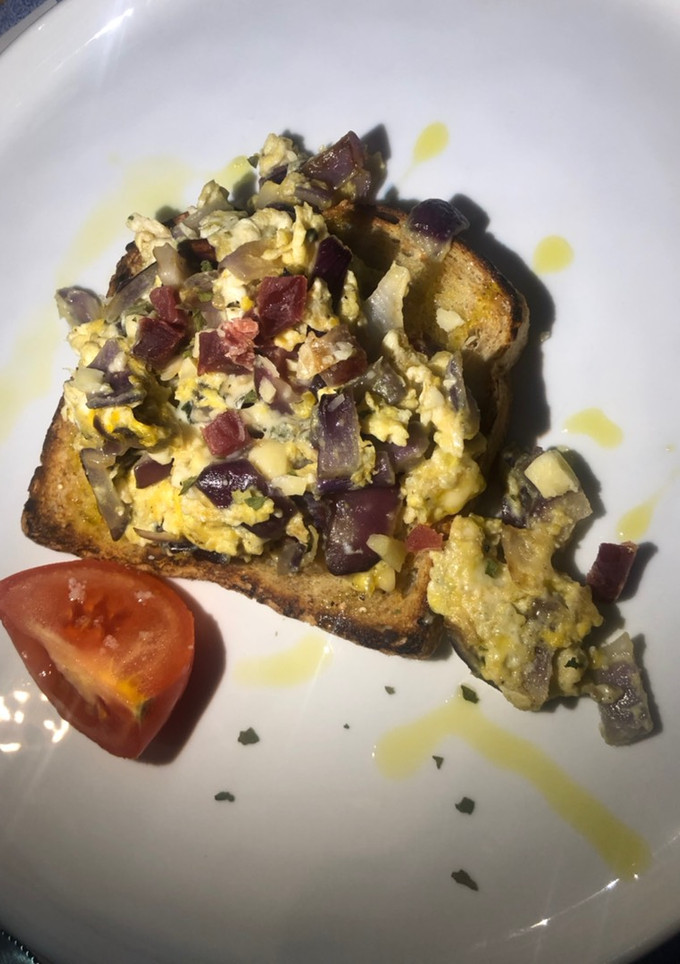 Una foto de Tosta de huevos revueltos con cebolla morada, cheddar, queso azul y jamón.🍞