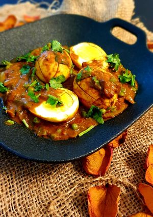 A picture of Boiled egg curry with peas.