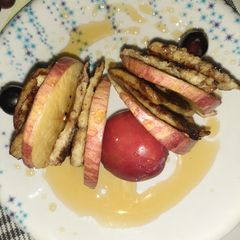 A picture of Banana pancake with apple and grapes sticks.
