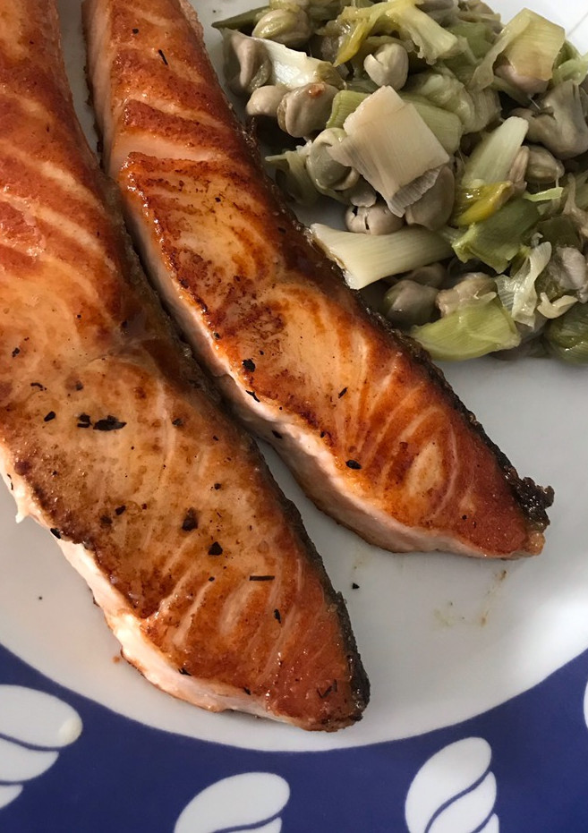 Una foto de Salmón fresco a la plancha con habitas y ajos tiernos